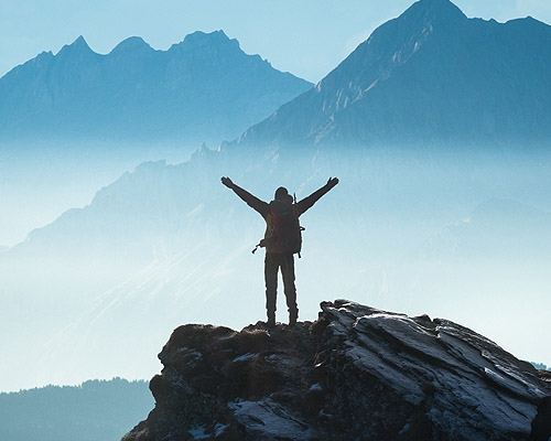 Man on top of mountain raising hands