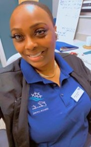 Pictue of African-American woman with blue colored shirt and black jacket. 