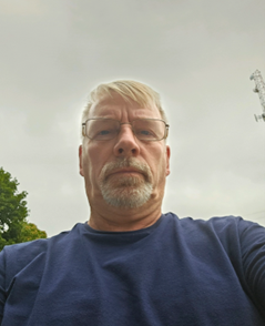 Picture of older white man with glasses wearing a blue sweatshirt.