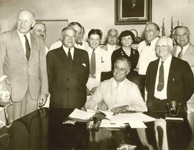 Secretary Frances Perkins standing directly behind President Franklin D. Roosevelt during the signing ceremony for the Social Security Act (1935).